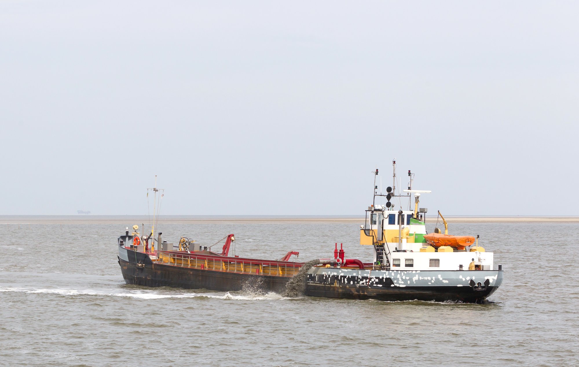 Tugboat towing dredge barge in coastal waters
