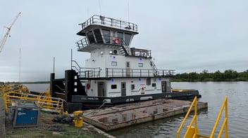 The M/V Lulu Hamilton pushboat docked at a shipyard, viewed from the dock
