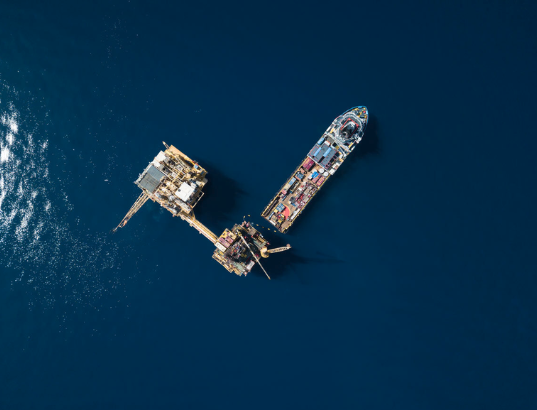 Aerial view of offshore support vessel docked at oil platform in open water
