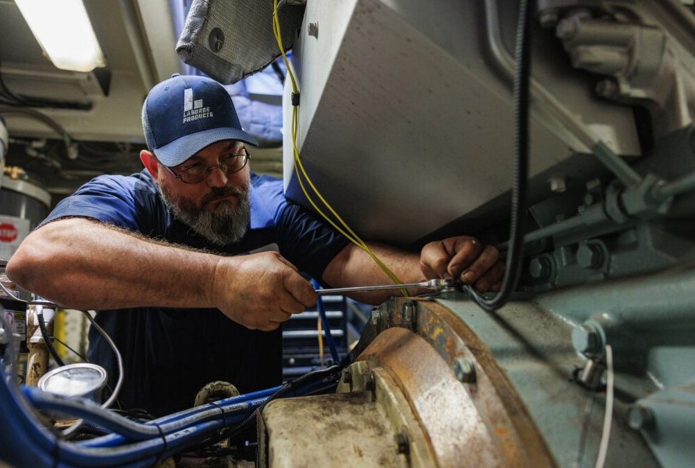 Technician repowering marine diesel engine inside vessel engine room